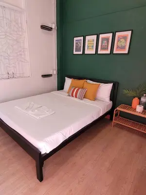 a large bed in a room with a green wall at The Open House Cafe and Hostel in Bangkok