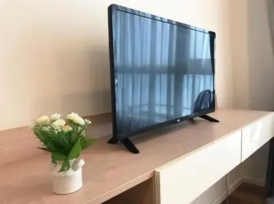 a television sitting on a table with a vase of flowers at Private Comfy Near BTS&MRT Sukhumvit Minimum 14 nights in Bangkok