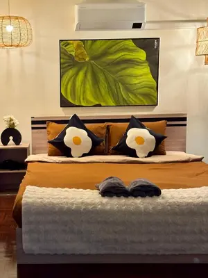 a bed with two pillows and a painting on the wall at 4BR 10PAX Ensuite Near EmQuartier Emporium Emsphere in Khlong Toei