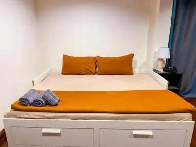a bed with an orange blanket and towels on it at 4BR 10PAX Ensuite Near EmQuartier Emporium Emsphere in Khlong Toei
