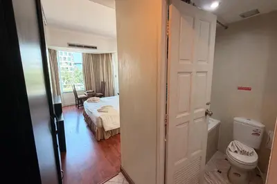 a bathroom with a toilet and a room with a bed at The Grand Imperial in Ban Song Hong