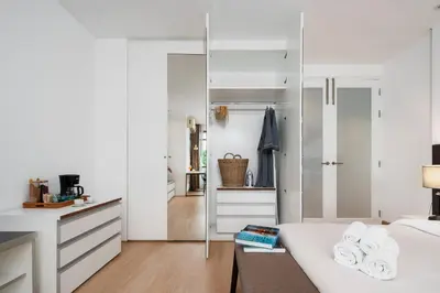 a bedroom with white walls and a bed with a mirror at Quiet Asoke/Nana BTS Retreat w/ Skyline & Gym/Park in Khlong Toei
