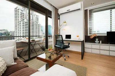 a living room with a couch and a desk at Quiet Asoke/Nana BTS Retreat w/ Skyline & Gym/Park in Khlong Toei