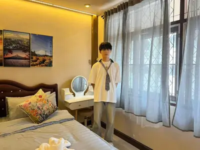 a boy standing in front of a bed in a bedroom at Moochi Home Ratchada in Bangkok