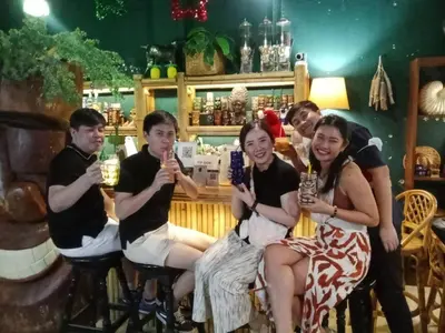 a group of people sitting at a bar with drinks at Carl and Ellie Home in Bangkok