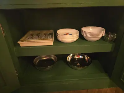 a green cabinet with plates and bowls on a shelf at Carl and Ellie Home in Bangkok