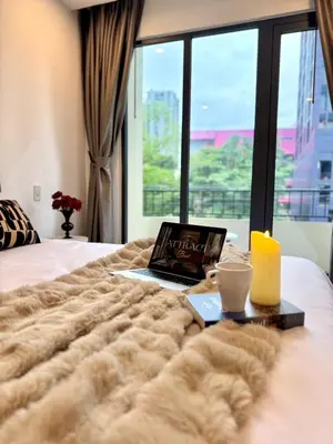 a laptop computer sitting on top of a bed with a window at Common Living Ekkamai in Bangkok