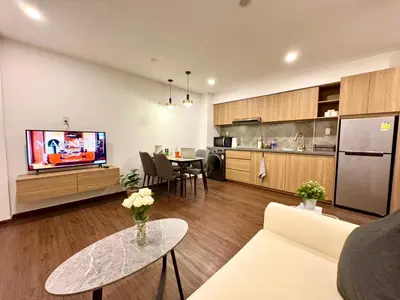 a living room with a couch and a tv and a kitchen at Common Living Ekkamai in Bangkok