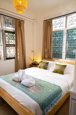 a bedroom with two beds and two windows at Bangkok Neighborhouse in Bangkok