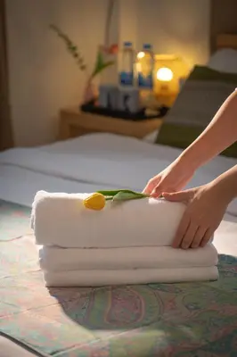 a person is preparing towels on a bed at Bangkok Neighborhouse in Bangkok