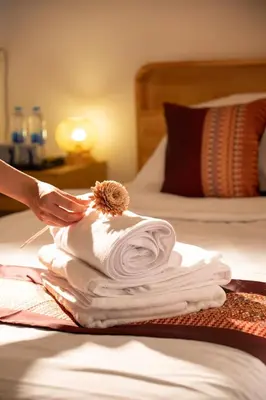 a person is drying towels on a bed at Bangkok Neighborhouse in Bangkok