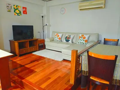 a living room with a couch and a tv at At Sathon apartment in Bangkok