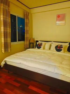 a bedroom with a large white bed with a window at At Sathon apartment in Bangkok