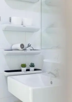 a white bathroom with a sink and two plants at Downtown Spacious Luxury Condo BKK- 5 mins BTS! in Bangkok