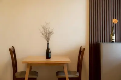 a table with a bottle of wine and a vase on it at Monument Stay in Bangkok