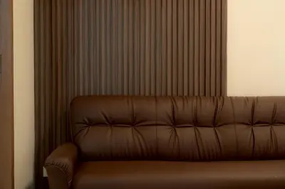 a brown leather couch sitting in front of a curtain at Monument Stay in Bangkok