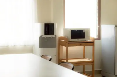 a room with a table and a tv and a refrigerator at Monument Stay in Bangkok