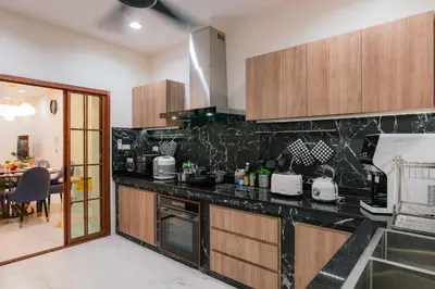 a kitchen with black counter tops and wooden cabinets at EXCLUSIVE SUKHUMVIT RESIDENCE, 3 Min BTS, Thonglor, 20 Guests in Bangkok