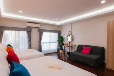 a hotel room with two beds and a chair at EXCLUSIVE SUKHUMVIT RESIDENCE, 3 Min BTS, Thonglor, 20 Guests in Bangkok