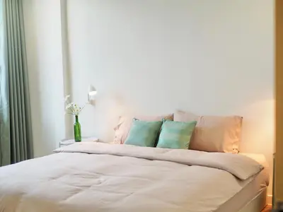 a white bed with three blue pillows on it at Cozy home with car parking near MRT Lat Phrao & Phawana in Bangkok