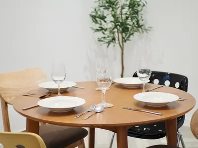 a wooden table with plates and wine glasses on it at Cozy home with car parking near MRT Lat Phrao & Phawana in Bangkok
