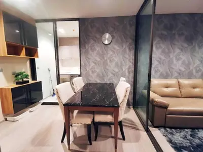 a dining room with a table and chairs and a couch at Life asoke rama 9 in Bangkok
