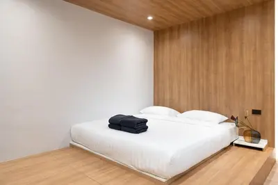 a bedroom with a white bed with a black bag on it at Townhouse at Sathu Pradit road in Bangkok