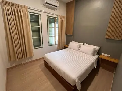 a bedroom with a bed with white sheets and a window at Ni Haus, cozy place for 4 people in Bangkok