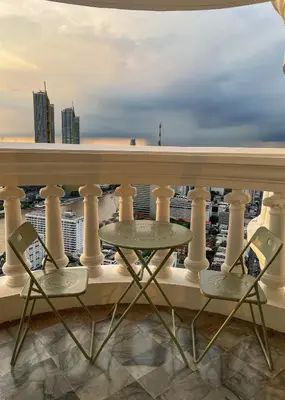 a balcony with two chairs and a table at Panoramic River View Residence in Bangkok