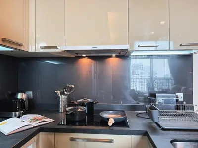a kitchen with white cabinets and a black counter top at Near BTS - High Floor - Pool and Gym - Sontana in Bangkok