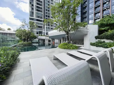 a patio with white chairs and trees and buildings at Near BTS - High-Floor - Rooftop Pool - Sontana in Bangkok
