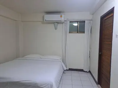 a white bedroom with a bed and a window at BaanSathorn21 in Bangkok