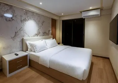 a bedroom with a large white bed and a television at Solumie Boutique Hotel in Bangkok
