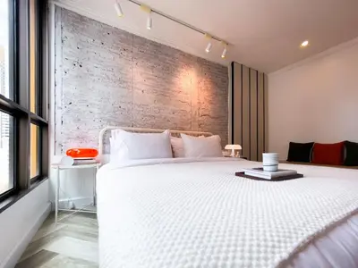 a bedroom with a white bed and a brick wall at Prime Chidlom 50sqm l Large Kitchen l Walk to BTS l Wifi in Bangkok