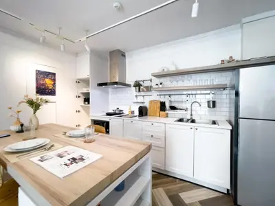 a kitchen with white cabinets and a wooden counter top at Prime Chidlom 50sqm l Large Kitchen l Walk to BTS l Wifi in Bangkok