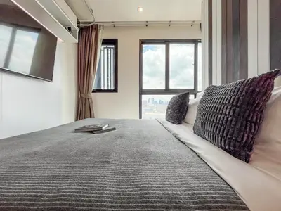 a bedroom with a large bed with two windows at Near MRT l Modern 2BR l Pool and Gym l Sontana in Bangkok