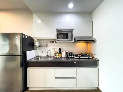 a kitchen with white cabinets and a stainless steel refrigerator at Downtown Stay 65 sqm - Ultra-WiFi - BTS Ratchathewi in Bangkok