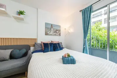 a bedroom with a bed and a couch and a window at Elio Sukhumvit 64 BTS Punnawithi in Amphoe Phra Khanong