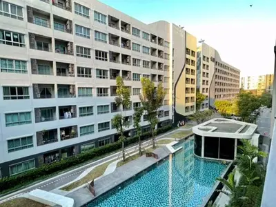 a large building with a swimming pool in front of a building at Elio Sukhumvit 64 BTS Punnawithi in Amphoe Phra Khanong
