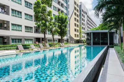 a large swimming pool with chairs and buildings at Elio Sukhumvit 64 BTS Punnawithi in Amphoe Phra Khanong