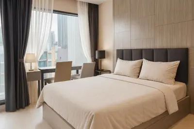 a bedroom with a large bed with a desk and a table at Stylish Sukhumvit 36 Condo Near BTS Thonglor in Bangkok