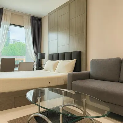 a living room with a bed and a couch and a glass table at Stylish Sukhumvit 36 Condo Near BTS Thonglor in Bangkok