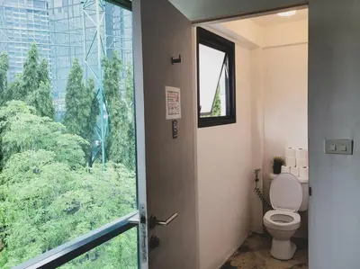 a bathroom with a toilet and a large window at HOLY SHEET Hostel in Bangkok