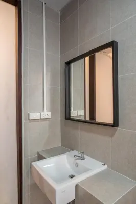 a bathroom with a sink and a mirror at Crownex Studio Deluxe in Bangkok