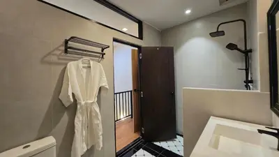 a white robe hanging on a wall in a bathroom at TownHouse near Central Ladprao with bathtub in Bangkok