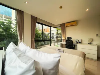 a bedroom with a bed with white pillows and a window at Vibe Sukhumvit 61 l Ultra WIFI l Walk to BTS Thonglor or Ekkamai in Bangkok