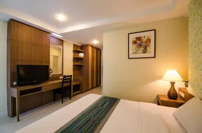 a hotel room with a bed and a desk with a television at The Platinum Suites Bangkok by Dancenter in Bangkok