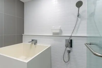 a white bathroom with a shower with a sink at Luxury Loft with Stunning 25th Floor View in Bangkok