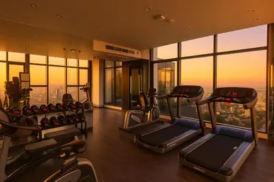 a gym with cardio equipment in a building with windows at Luxury Loft with Stunning 25th Floor View in Bangkok