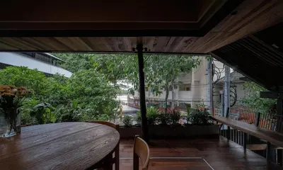 a table and chairs in a room with a large window at Vanich House - Mechanic's Room in Bangkok